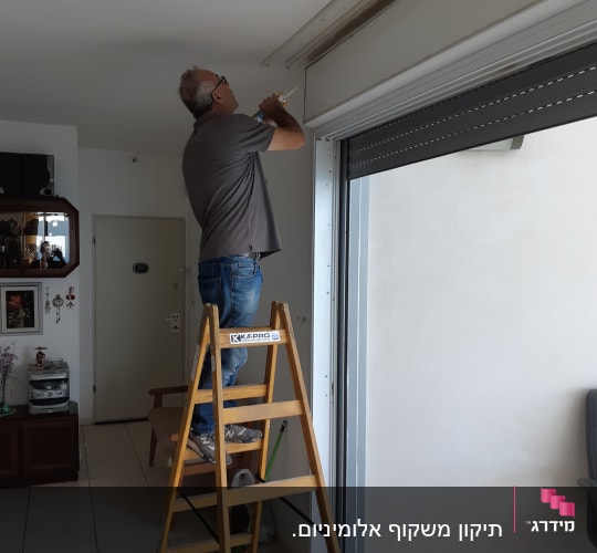 אדם עובד על מסגרת אלומיניום של חלון